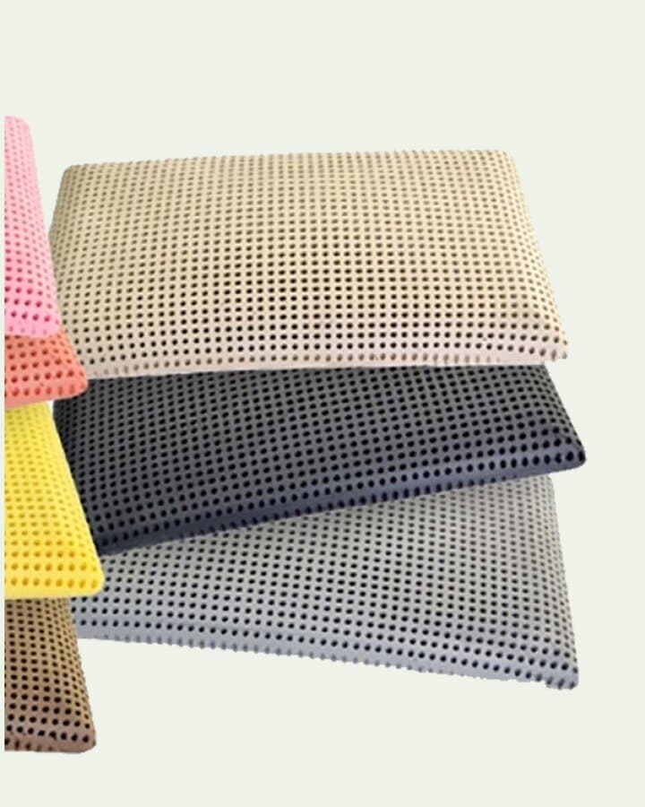 Guanciali traforati impilati, nei toni beige, grigio e giallo